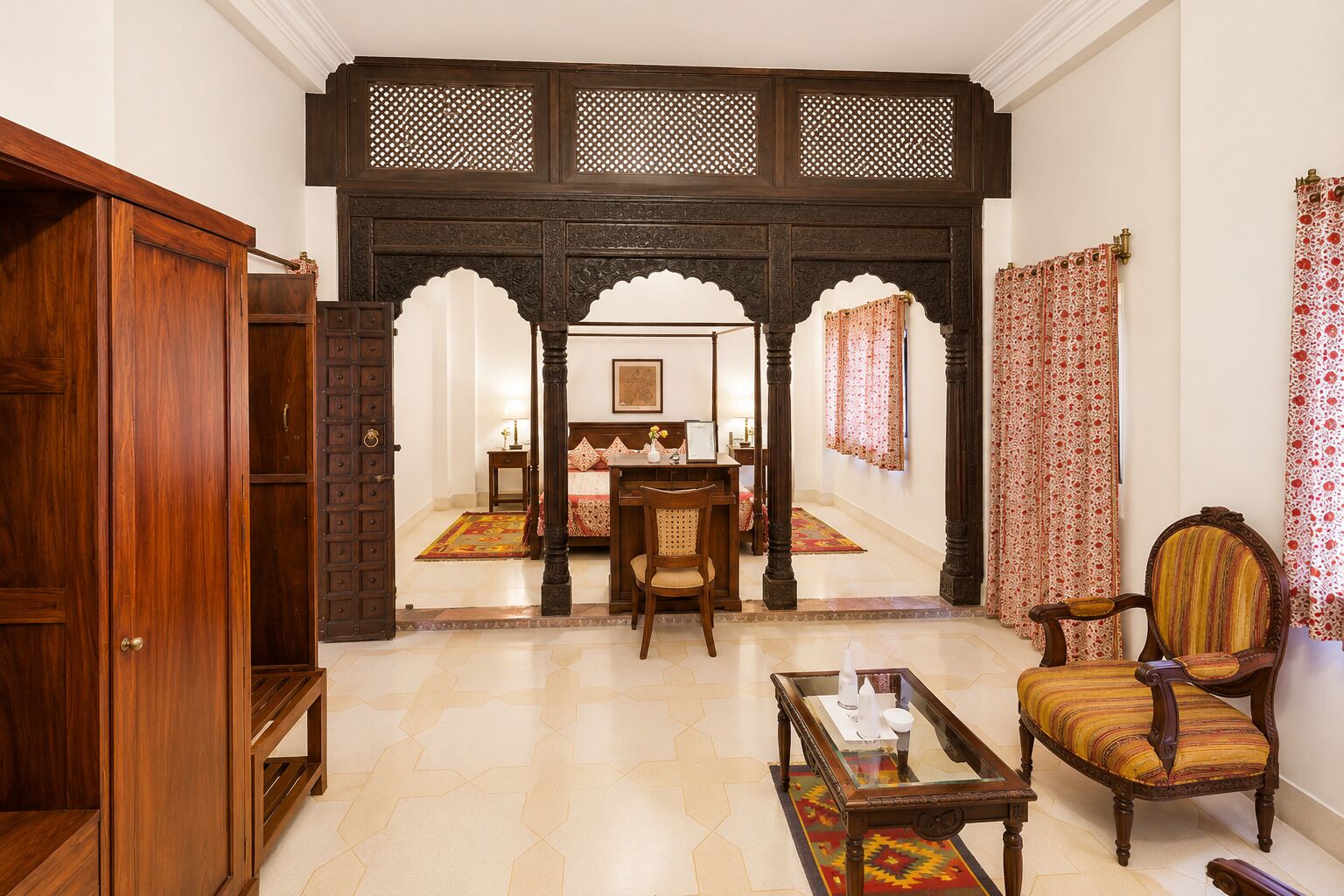 A traditional room with a wooden door, a bed with a canopy, a dining table, and a chair.