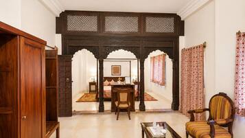 A traditional room with a wooden door, a bed with a canopy, a dining table, and a chair.