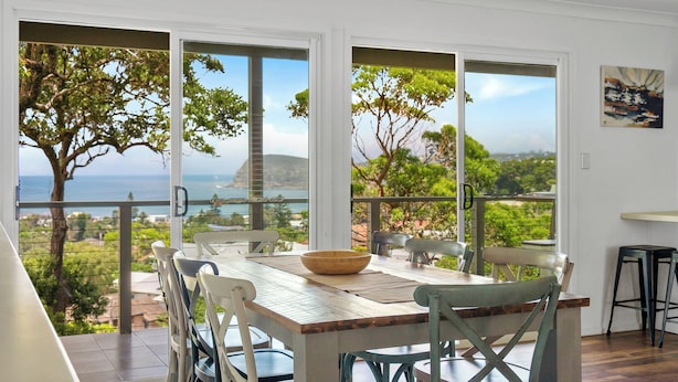 Un espace repas avec vue sur la mer, une table en bois et des chaises.