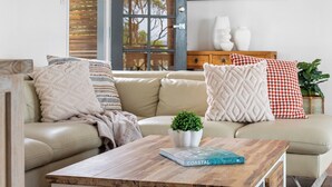 Un salon moderne avec un canapé beige, une table basse en bois et une plante en pot.
