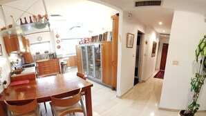 A spacious kitchen with a dining area, wooden cabinets, a refrigerator, and a potted plant. - Spacious Penthouse-5 Rooms apartment in Best location  (Jerusalem)