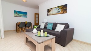 Una sala de estar moderna con un sofá gris, una mesa de centro de madera y un comedor con una mesa y sillas de madera.