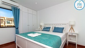 Ein sauberes und helles Schlafzimmer mit einem Bett, einem Nachttisch und einem Fenster mit Vorhängen.