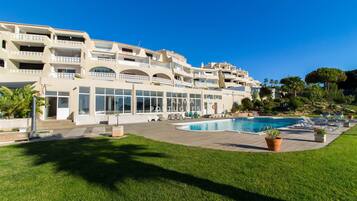 Un hotel con piscina, mobiliario exterior y un césped bien cuidado.