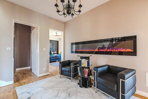 Een moderne woonkamer met een open haard, leren banken en een boekenkast.