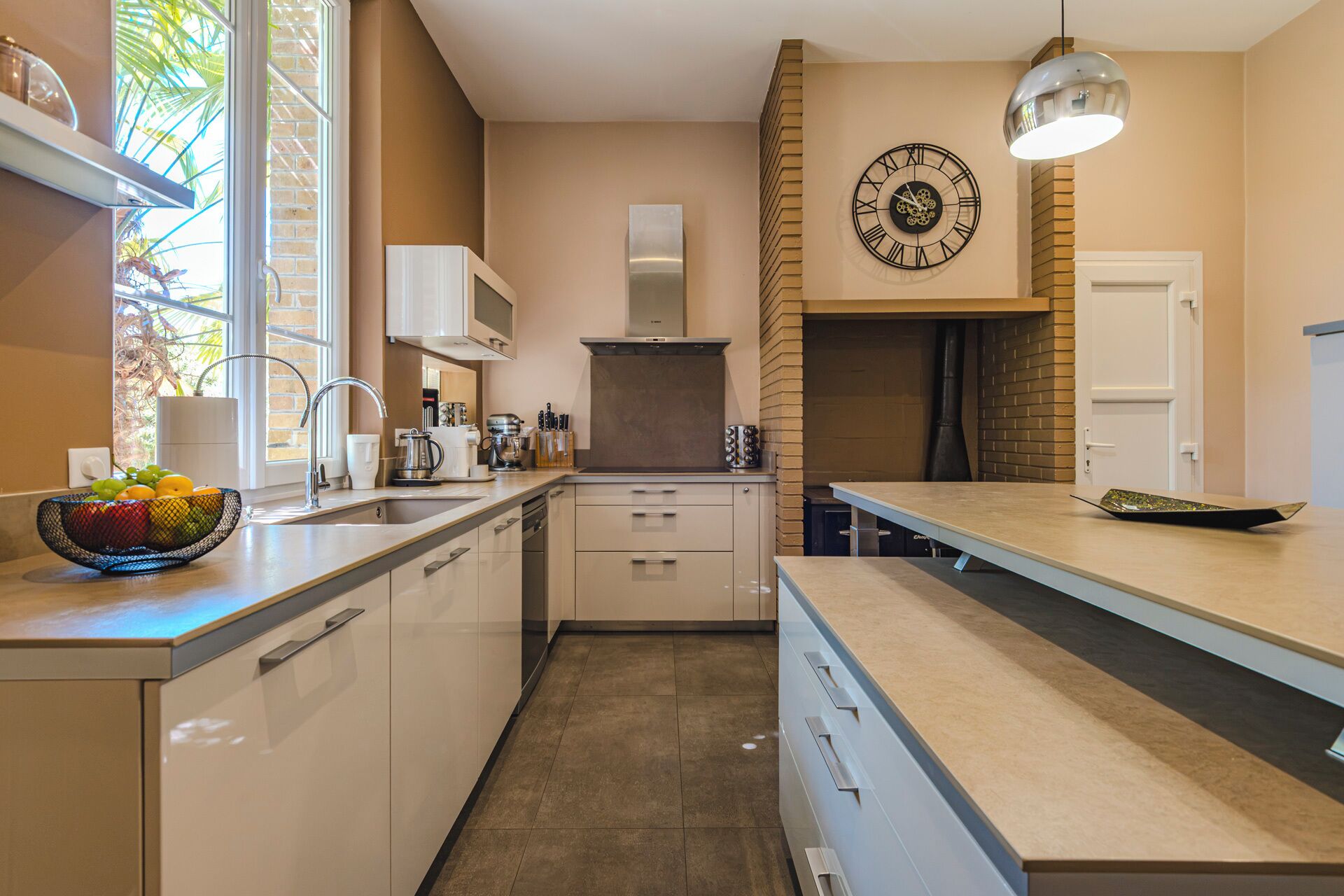 A modern kitchen with a built-in oven, a large window, and a clock on the wall.