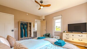 Een slaapkamer met een bed, een kledingkast, een televisie en een plafondventilator.