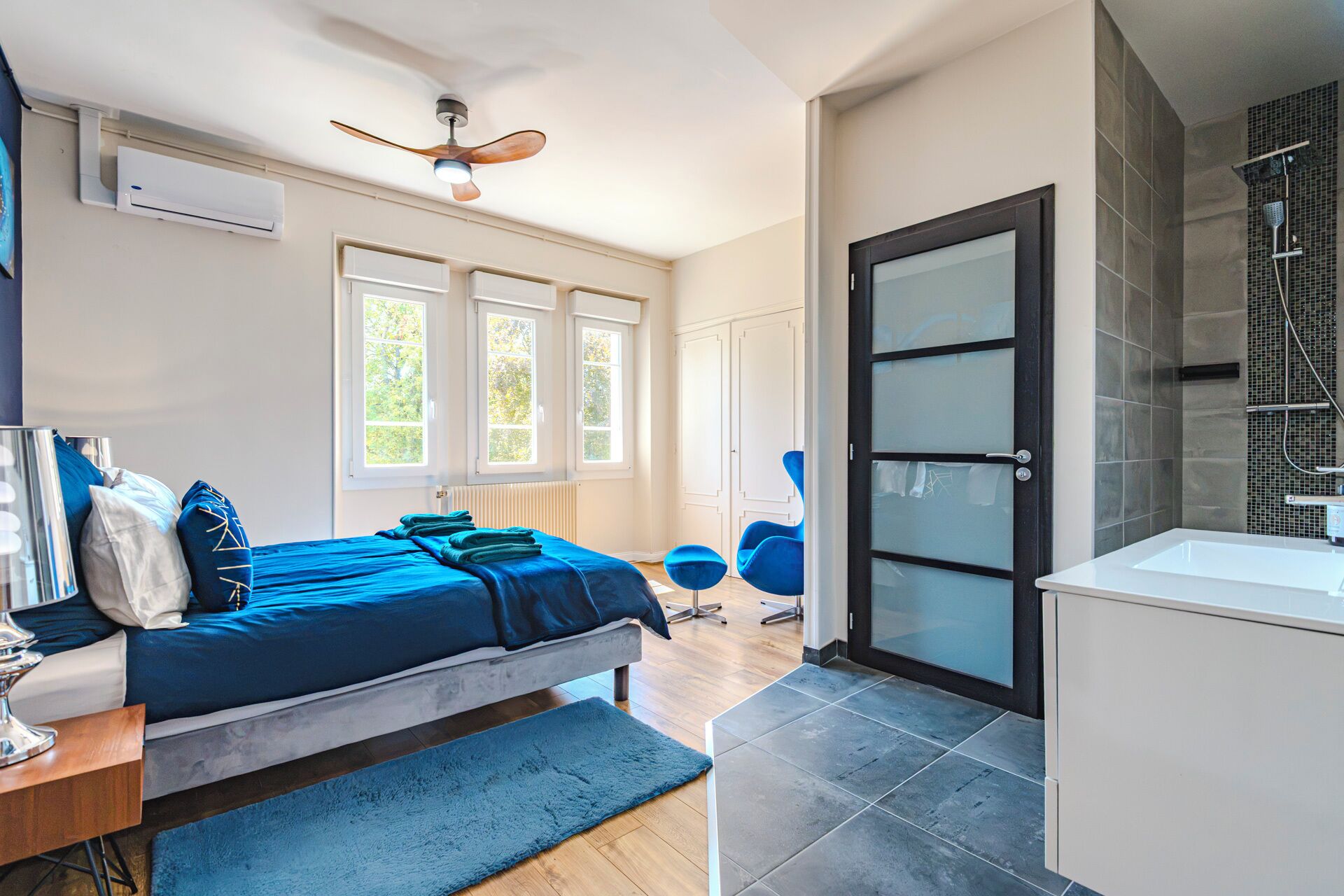 Un dormitorio moderno con una cama, un ventilador de techo y vistas al exterior.
