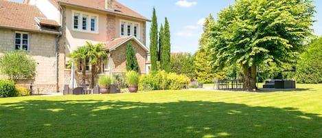 A large house with a well-maintained lawn and a variety of trees and shrubs.