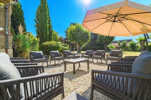 Een terras met rieten meubels en een parasol.