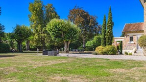 Een gazon met buitenruimte, een bakstenen gebouw, bomen en een zithoek.