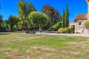 Un espace extérieur verdoyant, avec un bâtiment en briques, des arbres et des sièges.
