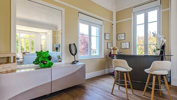 A modern kitchen with a white countertop, two bar stools, and a large window.