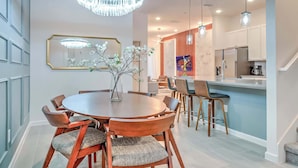 A modern dining area with a round table, chairs, and a chandelier.