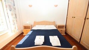 A neatly made bed with a blue bedspread, two white towels, wooden headboard, bedside tables, and a wardrobe. - Refúgio da Falésia By D´alma Portuguesa (Albufeira)