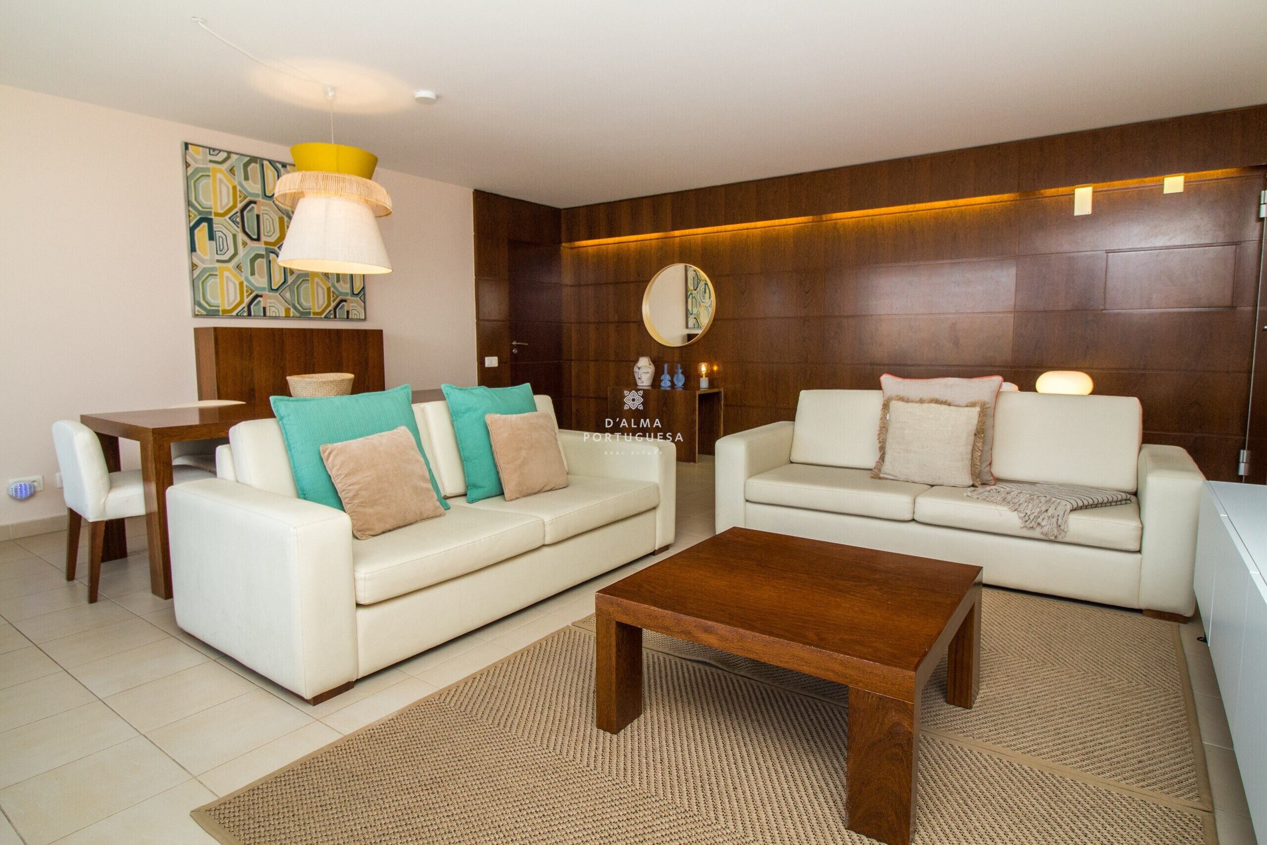 Ein modernes Wohnzimmer mit zwei weißen Sofas, einem Holztisch und einem Esstisch mit Stühlen.