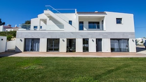 Une maison moderne à deux étages, dotée d’un toit plat, de grandes fenêtres et d’un escalier apparent menant à l’étage supérieur.
