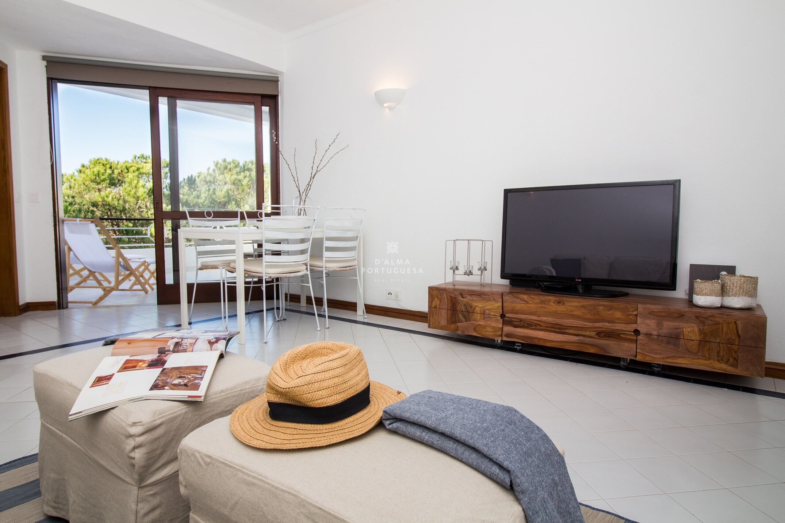 Uma sala de estar com sofá, televisão, um armário de madeira e um espaço de refeições com cadeiras e mesa.