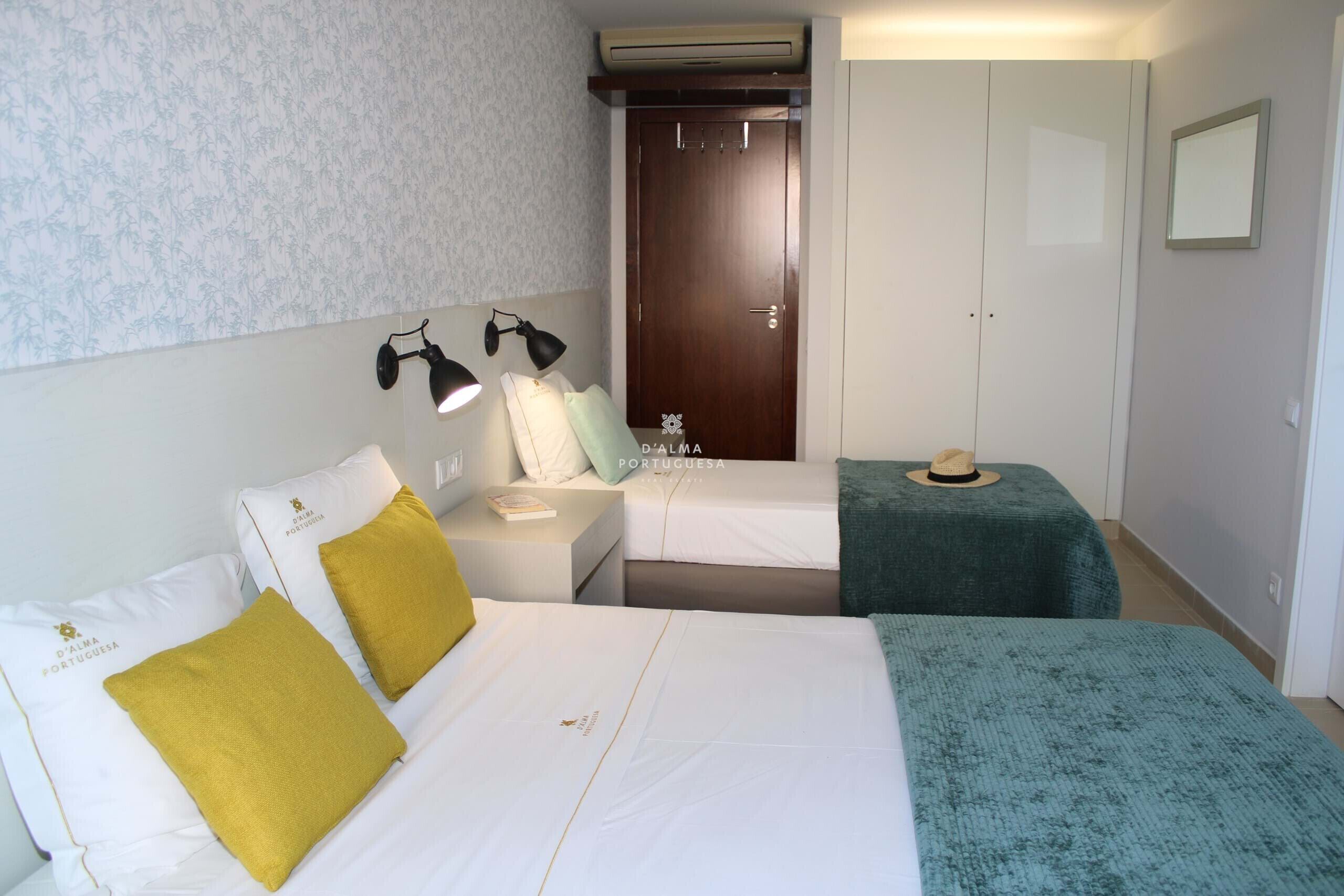 Ett hotellrum med två sängar, en garderob, en spegel och ett nattduksbord med lampor.