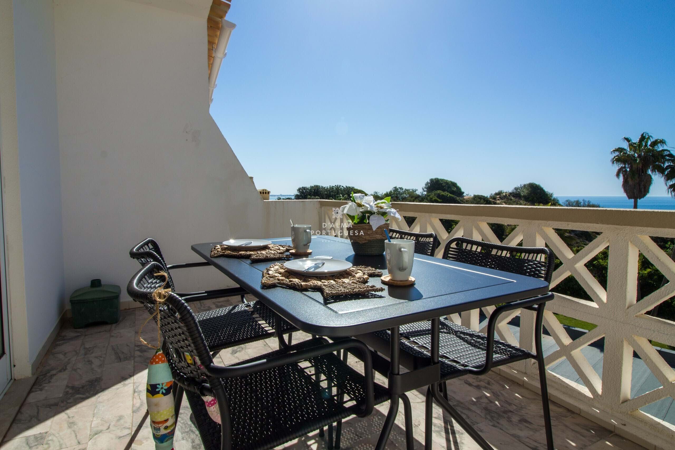 A balcony with a table set for two, overlooking a scenic view.