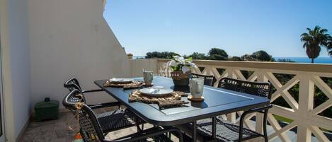 A balcony with a table set for two, overlooking a scenic view.