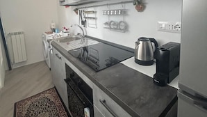 Een moderne keuken met een ingebouwde oven, een koffieapparaat en een waterkoker.