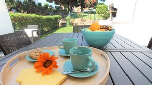 Una mesa con una bandeja que contiene una galleta, una servilleta amarilla, una taza azul, un bol azul con naranjas y un platito azul con una cuchara.