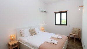 Un dormitorio con cama, lámparas de noche, una ventana y una silla.