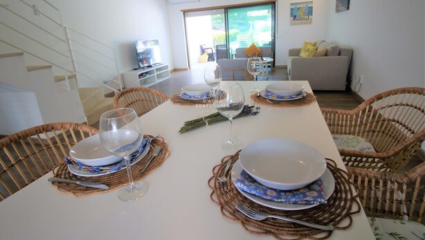 Comedor con una mesa dispuesta para cuatro personas, rodeado de sillas de mimbre.