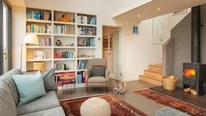 Un salon chaleureux avec une cheminée, une bibliothèque, un canapé et un tapis.