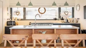 Une cuisine moderne dotée d’un îlot central, de luminaires suspendus, de décorations en forme de cœur et de bancs en bois.