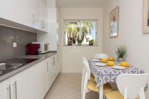A kitchen with white cabinets, a red appliance, and a dining area with a table set for four.