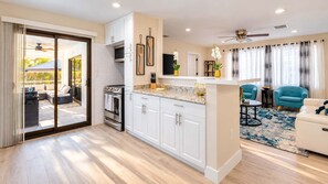 A modern kitchen with white cabinets, a built-in oven, and a large island with a granite countertop.
