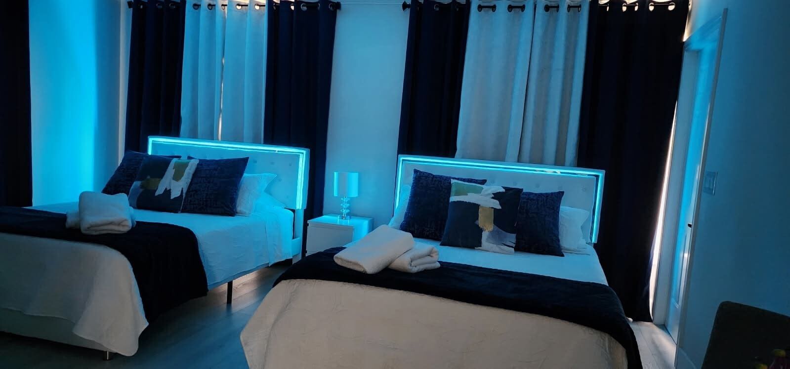 Ein Hotelzimmer mit zwei Betten, jeweils mit Kopfteil, Nachttischen und einer Lampe.