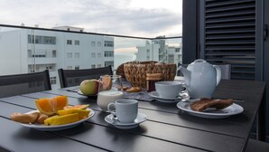 A balcony table with breakfast items including orange slices, milk, a teapot, and a basket. - Apart Terraços do Mar D´alma Portuguesa (Loulé)