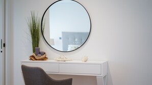 A white desk with a round mirror, a vase with green plants, and decorative items. - Apart Terraços do Mar D´alma Portuguesa (Loulé)
