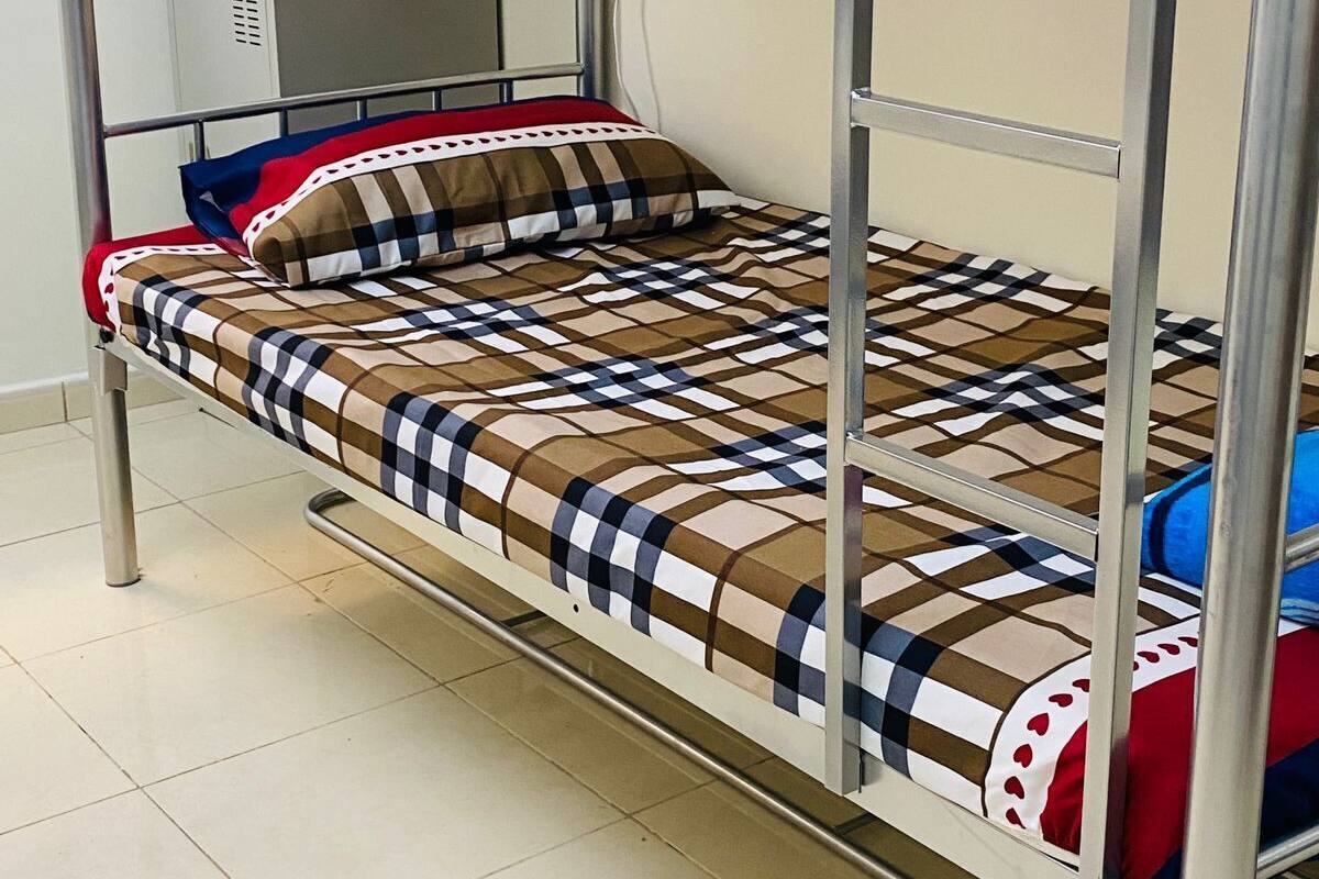 A bunk bed with a metal frame, a patterned bedspread, and a pillow with a checkered design.