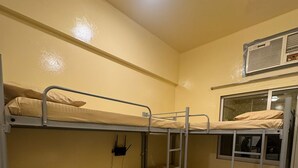Dormitorio con dos literas, una ventana y una unidad de ventilación.