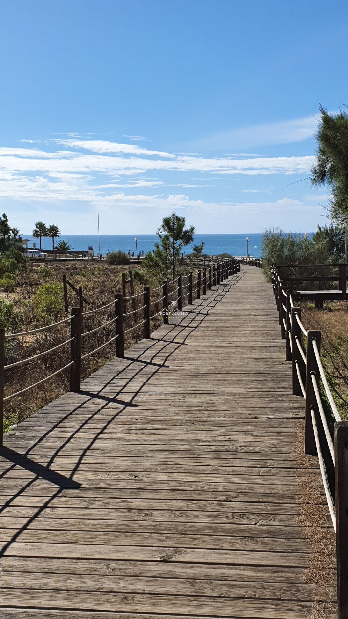Une promenade en bois qui mène à une plage, avec un ciel dégagé.