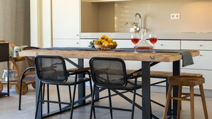 Una cocina con una mesa de madera, sillas negras y un frutero.