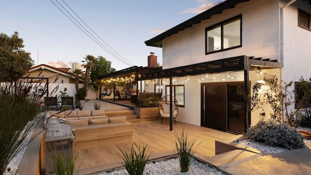 A modern house with a patio, outdoor seating, and a covered area with string lights.