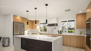 A modern kitchen with a large island, stainless steel appliances, and pendant lighting.