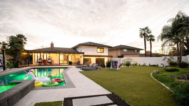 Une maison moderne dotée d’une piscine, d’une pelouse bien entretenue et d’un espace patio.