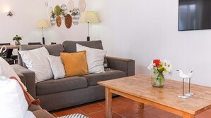 Un salon avec un canapé gris, une table basse en bois et un vase rempli de fleurs.