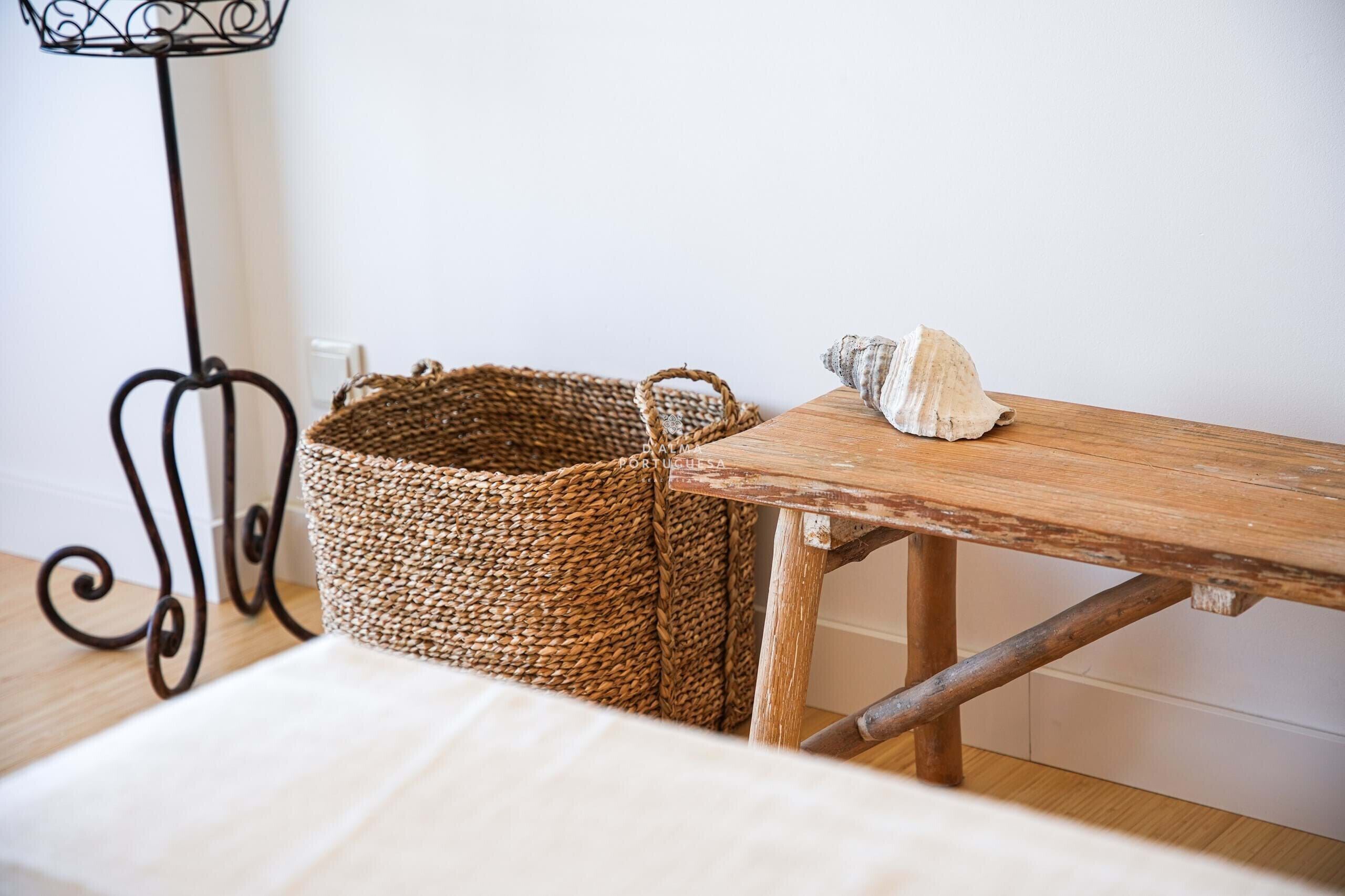 Una mesa de madera rústica con una cesta tejida y una concha marina.