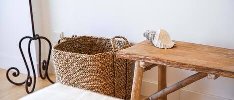 Una mesa de madera rústica con una cesta tejida y una concha marina.