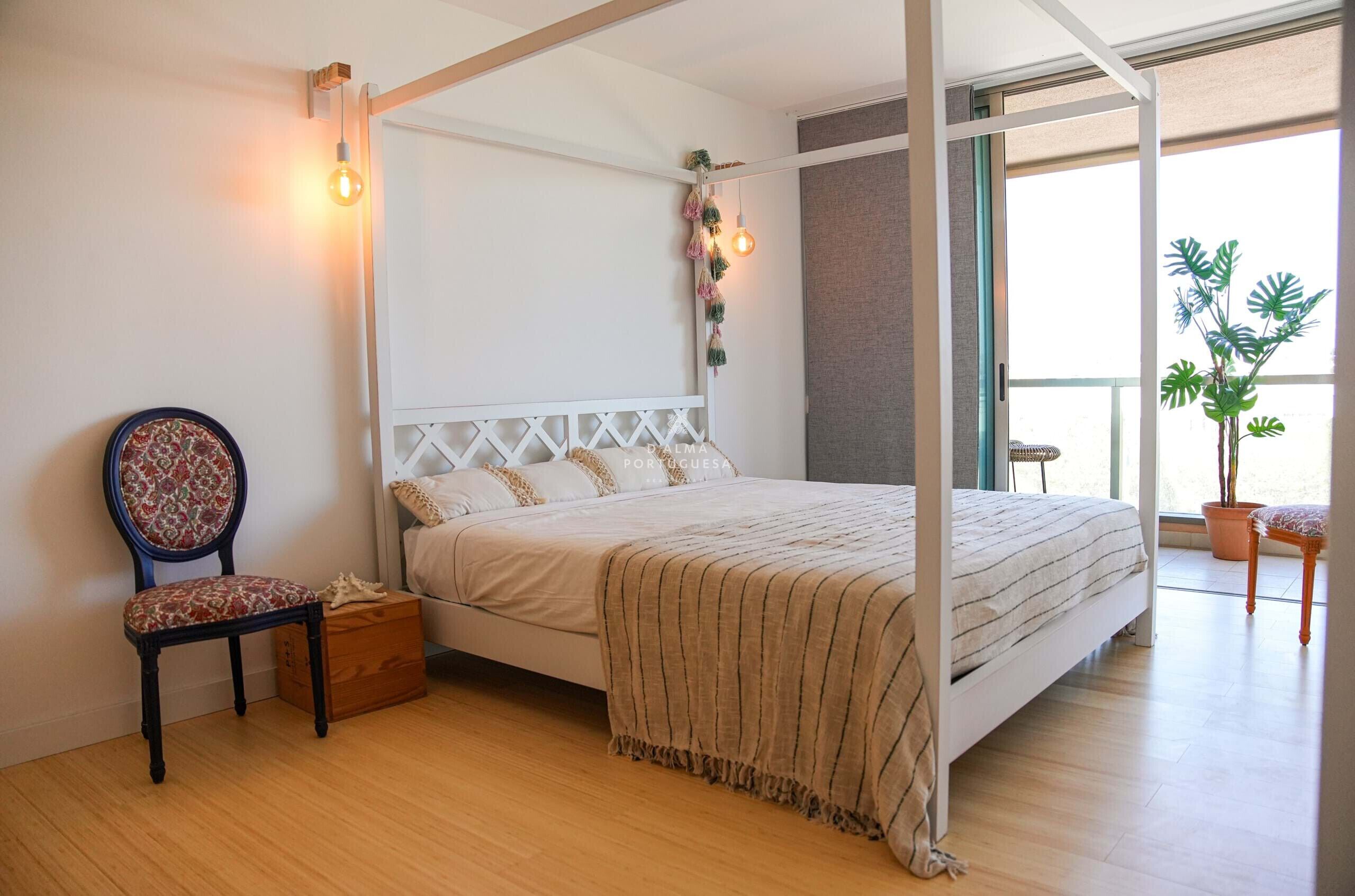 Une chambre à coucher avec un lit à baldaquin, une table de chevet en bois, une chaise et une plante en pot.