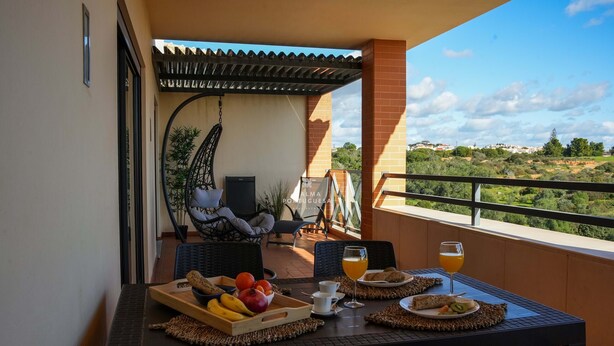 Een balkon met een ontbijttafel, inclusief fruit, brood en drankjes.