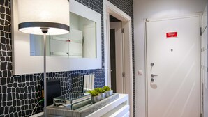 A modern bathroom with a mirror, a white door, and a sign indicating an emergency exit. - Apart Vilamoura Pine D'alma Portuguesa (Loulé)