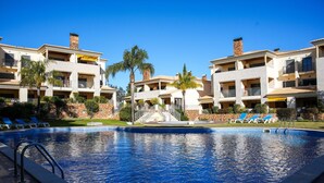 A hotel with a swimming pool, multiple balconies, and palm trees. - Apart Vilamoura Pine D'alma Portuguesa (Loulé)